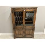 A CARVED OAK OLD CHARM STYLE BOOKCASE WITH LEAD GLAZED DOORS ABOVE CUPBOARD DOORS 95 X 136 X 33CM