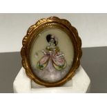 A GOLD PLATED OVAL HAND PAINTED MINIATURE BROOCH DEPICTING A LADY