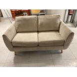 A MODERN TWO SEATER SOFA IN BEIGE FABRIC RAISED ON BEECH LEGS