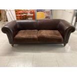 A 20TH CENTURY BROWN LEATHER CHESTERFIELD STYLE SOFA WITH STUD DETAILING RAISED ON MAHOGANY LEGS