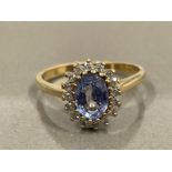 9CT GOLD OVAL TANZANITE STONE SET IN A CLAW SETTING SURROUNDED WITH A CLUSTER OF ROUND BRILLIANT CUT