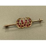 9CT GOLD DOUBLE HORSE SHOE BROOCH SET WITH RUBIES