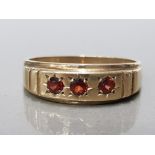 9CT YELLOW GOLD GENTS 3 STONE GARNET RING FEATURING 3 BRILLIANT ROUND CUT GARNETS SER ACROSS THE TOP