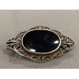 SILVER ORNATE STONE SET BROOCH WITH BLACK OVAL STONE SET IN THE CENTRE WITH FANCY EDGING 6.8G GROSS