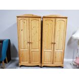 A PAIR OF PINE DOUBLE DOOR WARDROBES ON CASTORS