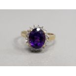 9CT YELLOW GOLD PURPLE AND DIAMOND CLUSTER RING FEATURING A OVAL PURPLE STONE SET IN THE CENTRE