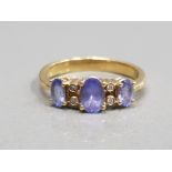 18CT YELLOW GOLD PURPLE STONE AND DIAMOND RING COMPRISING OF 3 OVAL PURPLE STONES SET WITH TWO