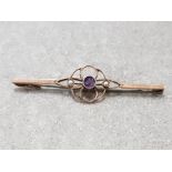 9CT YELLOW GOLD BAR BROOCH WITH CENTRE FLORAL STYLE COMPRISING OF CENTRAL AMETHYST FLANKED BY 2 SEED