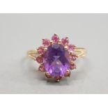 9CT YELLOW GOLD AMETHYST AND PINK STONE CLUSTER RING FEATURING A PURPLE STONE SET IN THE CENTRE