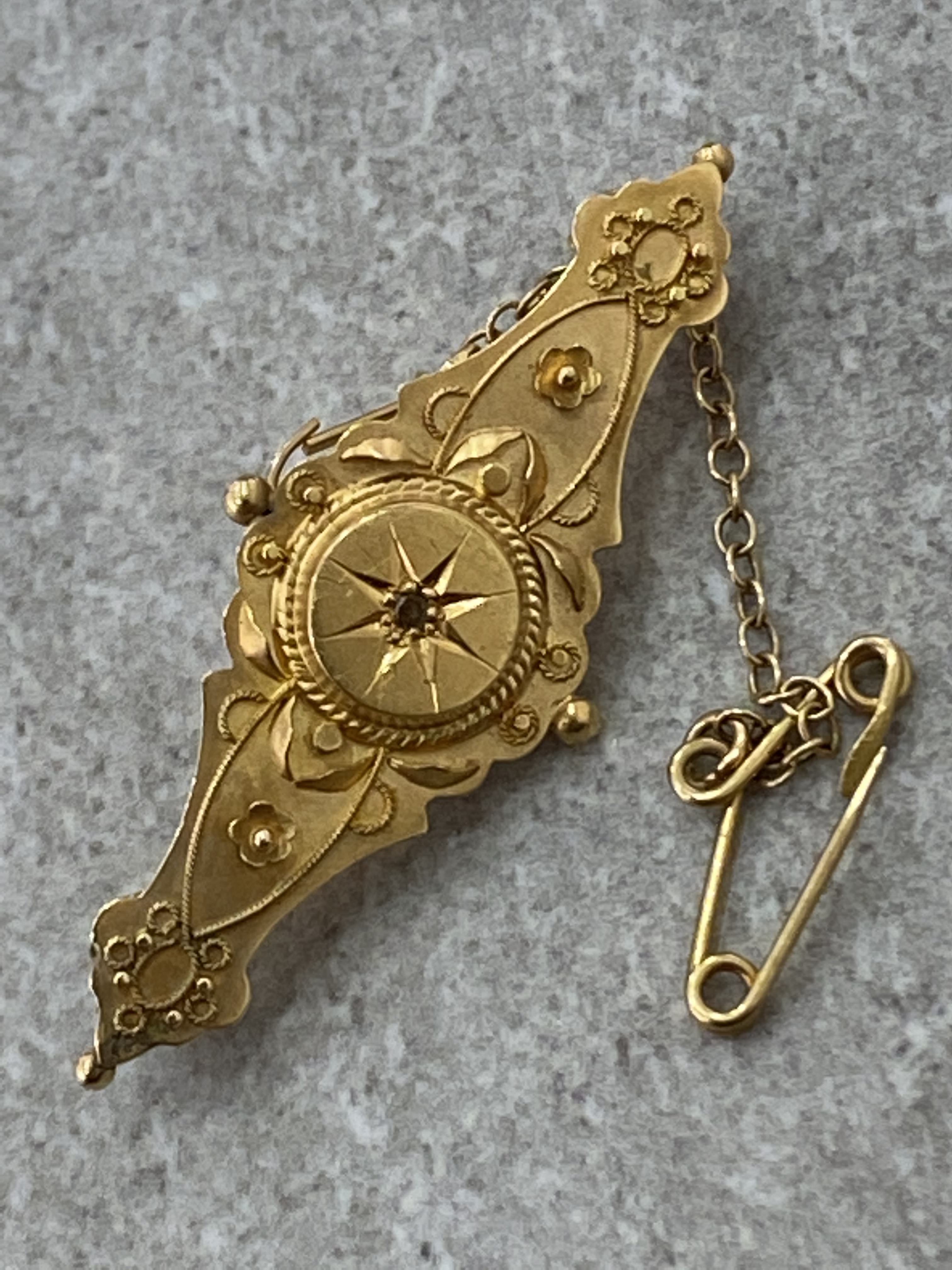 15CT GOLD ANTIQUE BROOCH WITH CENTRE STONE AND ENGRAVED PATTERN AND SAFETY CHAIN 2.6G