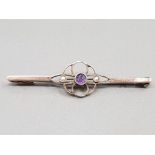 9CT YELLOW GOLD BAR BROOCH WITH CENTRE FLORAL STYLE COMPRISING OF CENTRAL AMETHYST FLANKED BY 2 SEED