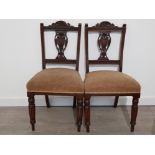 A PAIR OF EDWARDIAN HEAVILY CARVED MAHOGANY FRAMED CHAIRS WITH REEDED LEGS