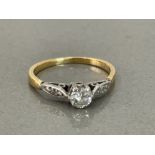 Gold diamond solitaire ring comprising of a single round cut diamond and diamonds on each shoulder