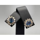 Gold sapphire and diamond cluster stud earrings set with a single oval sapphire surrounded by 12
