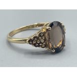 Ladies 9ct gold smokey quartz ring featuring a oval shaped stone in centre and 6 small Smokey quartz