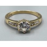 Ladies 9ct gold CZ ring. Featuring a round stone set in centre with 3 stones set on each shoulder.