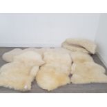 Four sheepskin rugs, the largest 183cm long, together with a faux sheepskin rug.