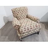 An early 20th century low armchair upholstered in patterned fabric.