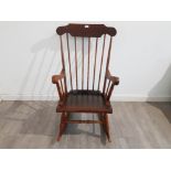 A stained wood rocking chair with windsor back.