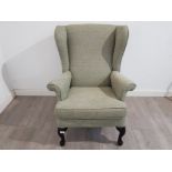 A parker knoll wingback armchir upholstered in green wool fabric.