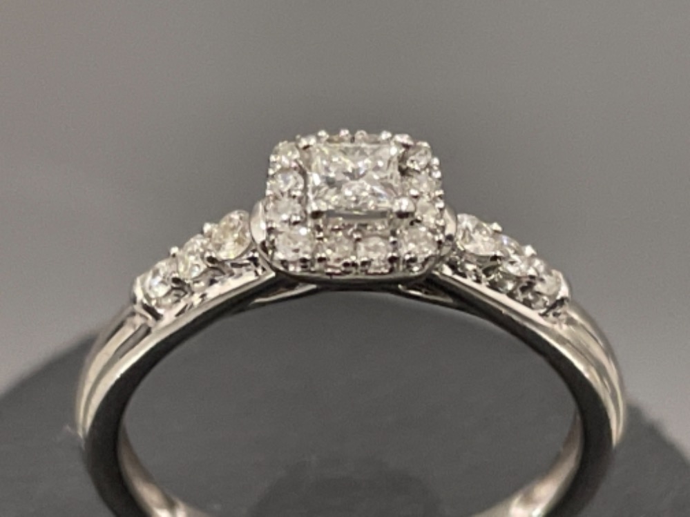 Ladies 9ct white gold diamond ring. Comprising Princess cut and surrounded by a halo of 12 round