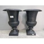 A pair of black painted cast metal urns 35cm high.