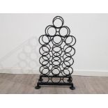 A heavy black painted metal bottle holder for 18 bottles 85.5cm high.