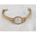 Ladies 9ct yellow gold omega watch, featuring round case set with silver dial + gold baton haw