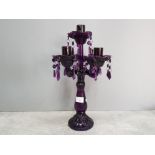 A purple moulded glass four branch candelabra with lustre drops 42cm high.