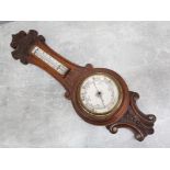 A Victorian oak cased aneroid barometer, scroll crested rail above thermometer and barometer dial,