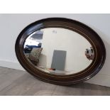 An oval bevelled wall mirror in wooden frame 82cm wide.