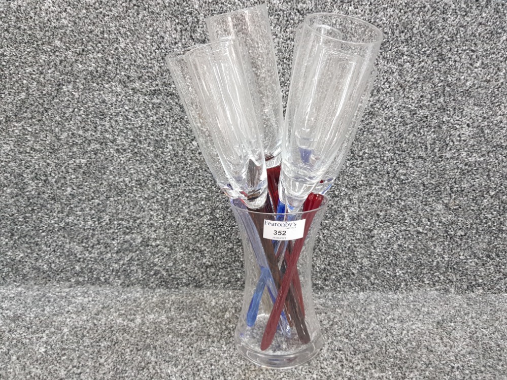 Nine champagne flutes, glasses with mixed colour stems and flute holder vase.