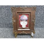 Cast glass baby's head in the style of Reekie, in ornate antique frame, with handmade brass stand.