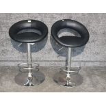 Two black leatherette adjustable breakfast bar stools.