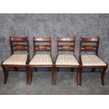 A set of four Regency style mahogany drop in seat dining chairs with brass inlay backs.