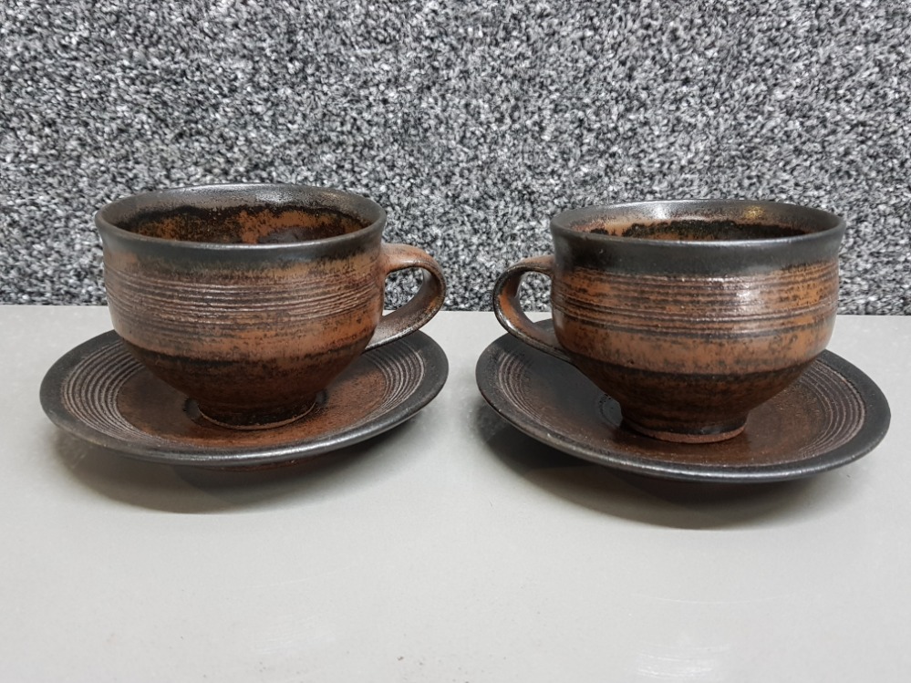 A good pair of cups and saucers by Gwyn Hanssen Pigott in rich Tenmoku glaze with impressed mark