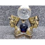 An Egyptian brass triform ornament with two glass balls 17cm high.