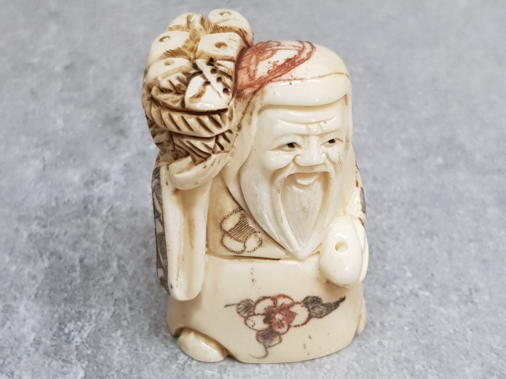 A finely carved bone netsuke of an elder with basket of bread.