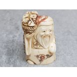 A finely carved bone netsuke of an elder with basket of bread.