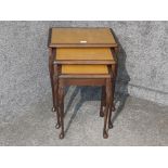 A mahogany nest of tables with leather and glass tops.