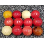 Twelve Edwardian ivory billiard/snooker balls, two natural and the others dyed red brown and