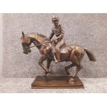 A large lacquered brass sculpture of a horse and jockey raised on rectangular plinth 74cm long