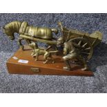 A brass group "Toil" depicting a man with his horse and cart and dog, on wooden plinth 44cm long.