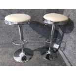 A pair of cream leatherette and chrome style breakfast bar stools.