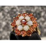 Ladies 9ct gold opal and red stone cluster ring. Set with 6 opals and 13 red stones.