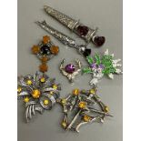 Scottish brooches to include a silver stag head with purple paste stone, a hardstone and metal cross