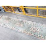 A Chinese wool runner with floral decoration on green ground 310 x 69cm.