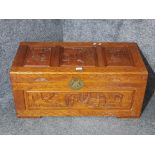 A carved wooden blanket box with brass fitting.