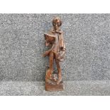 Tall wooden carving of a scholar with book in hand, with plinth being a pile of large books,