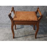 An antique walnut piano stool with contents.